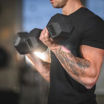 Determined Caucasian Male Athlete Working Out with Dumbbells