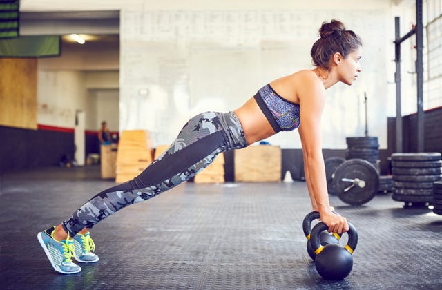 Determined fit athlete doing push-ups on kettlebells in gym
