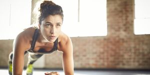 determined young woman performing plank position in gym