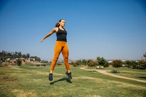 determined young women jumping while exercising at park against sky