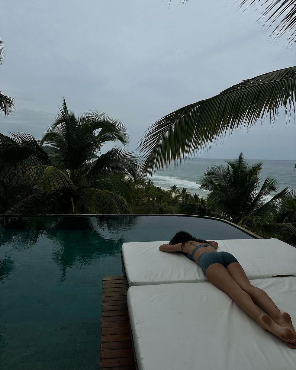 a person lying on a deck by a pool with palm trees