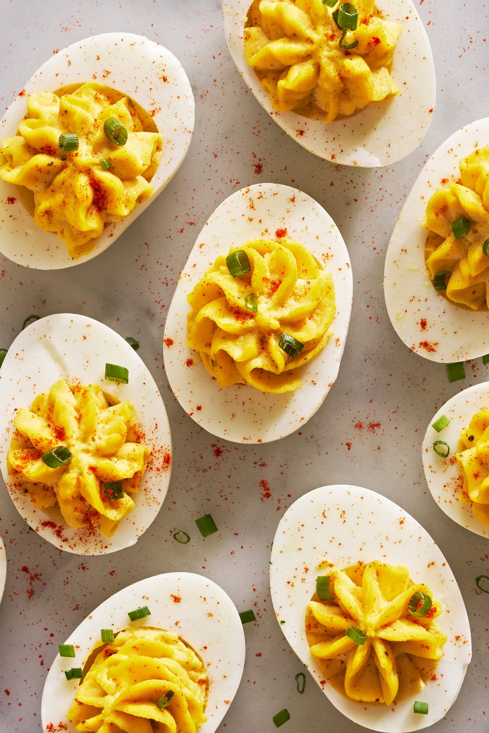deviled eggs piped in a star shape with paprika and chives