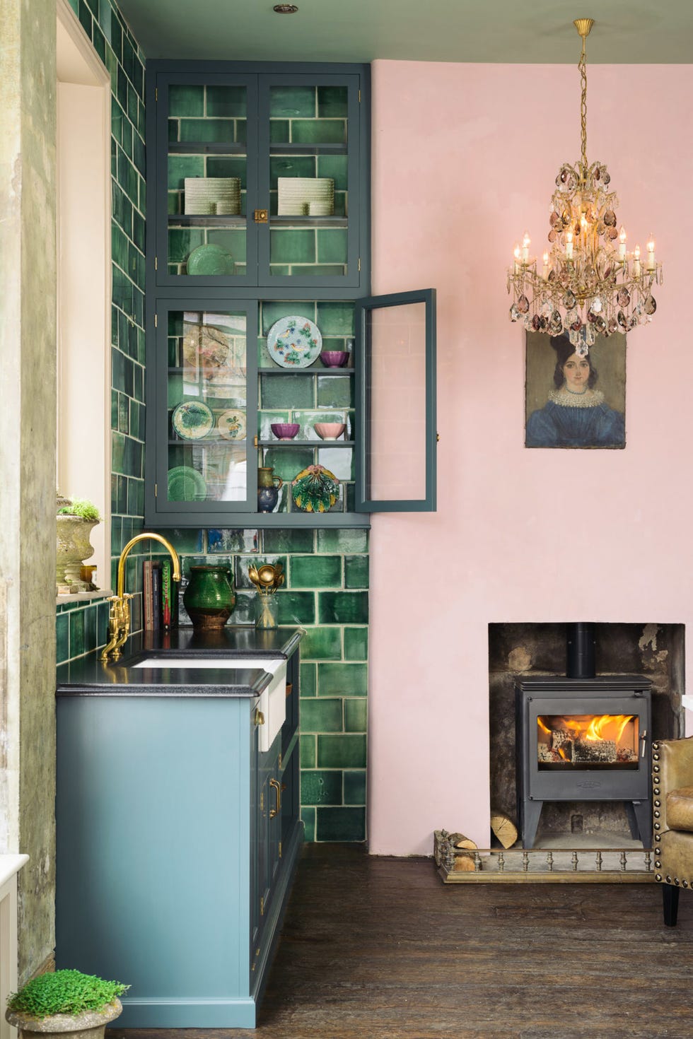 a cozy kitchen featuring green tiles a blue cabinet and a chandelier