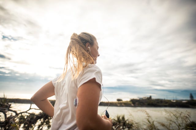 diabetic woman wearing glucose sensor running outdoors