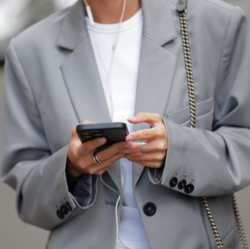 vrouw met grijze blazer en telefoon in hand