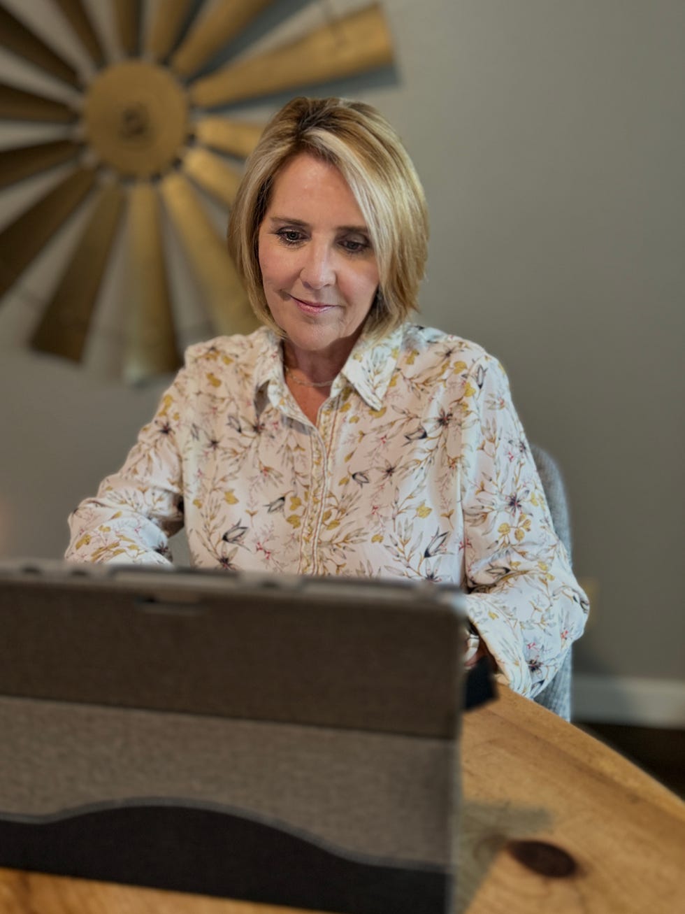 person seated at a table with a floral shirt and a tablet computer