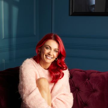 dianne buswell sat on red sofa wearing pink jumper