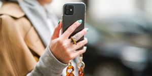 vrouw heeft telefoon in de hand met ketting, gouden ring, blauwe nagellak in parijs in februari 2021