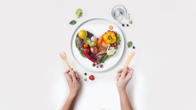 heart shape pile of sliced raw vegan food served on white background