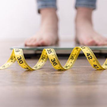 womens legs on the scales, close up of a measuring tape, the concept of losing weight, healthy lifestyle