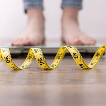 womens legs on the scales, close up of a measuring tape, the concept of losing weight, healthy lifestyle