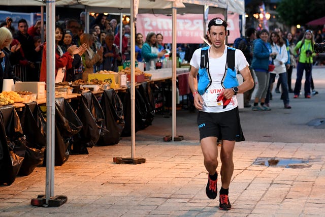 el corredor español de montaña kilian jornet corre por delante de un avituallamiento en al utmb