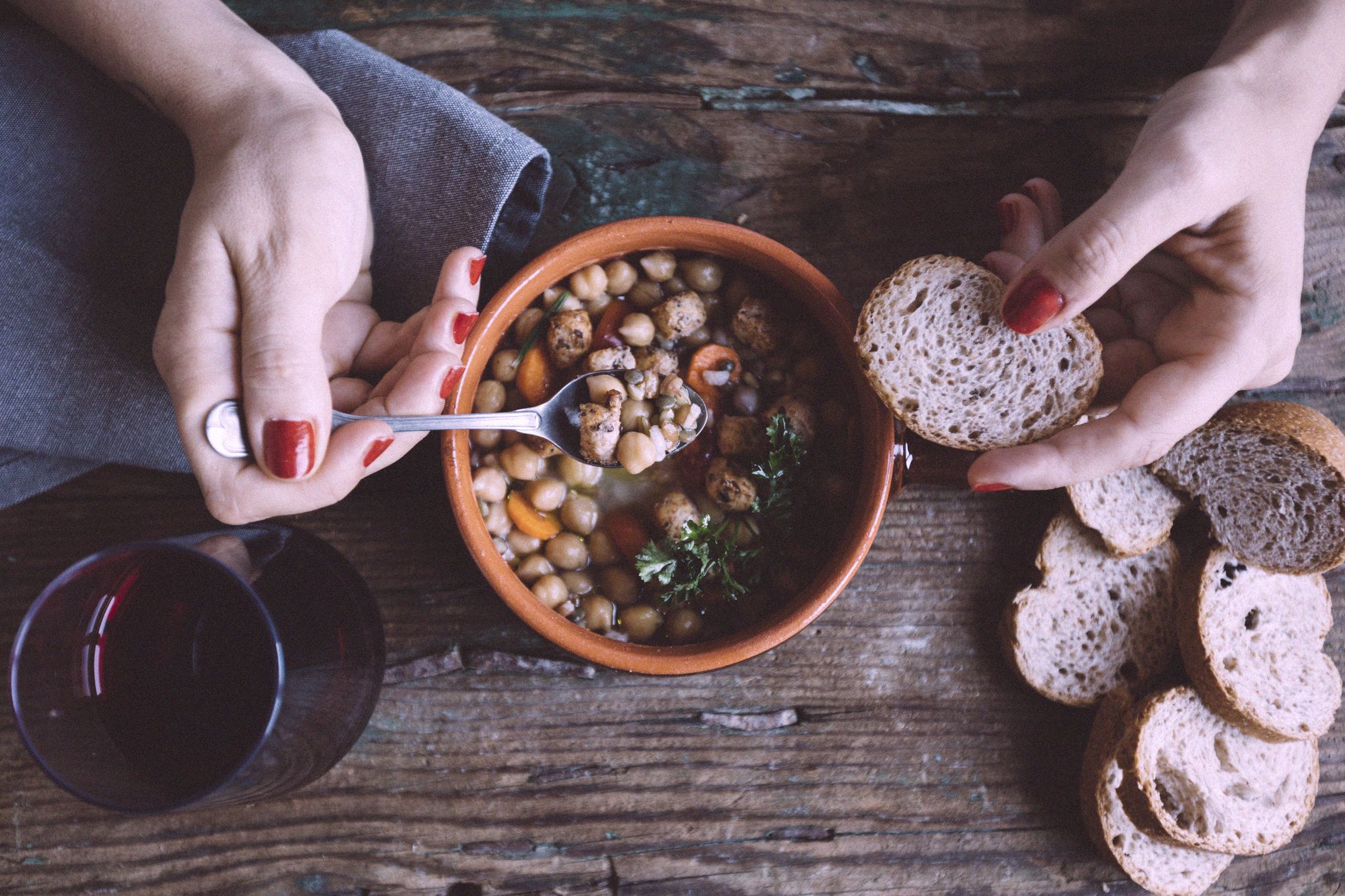 Woman eating Mediterranean soup with bread, close-up
