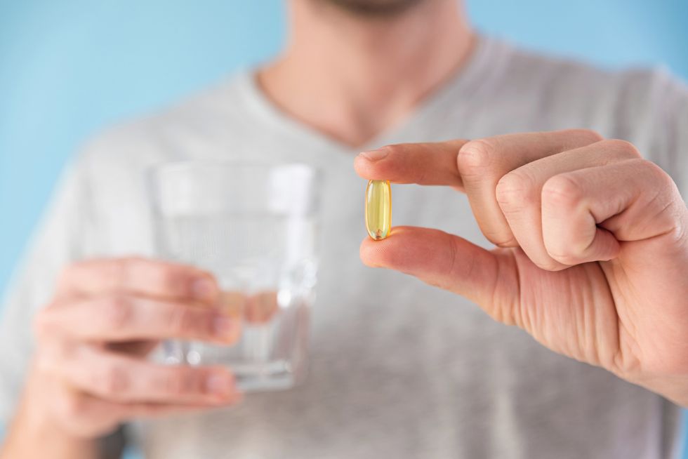 dietary supplements man holding omega 3 capsule with glass of water morning dose of vitamin d fish oil in pills