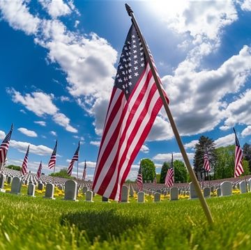 us flags on graves with simple marble headstones on sunny day with blue sky there is a flag front and center