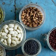 different types of beans like butter beans, pinto beans and black beans in jars on blue rustic wooden surface