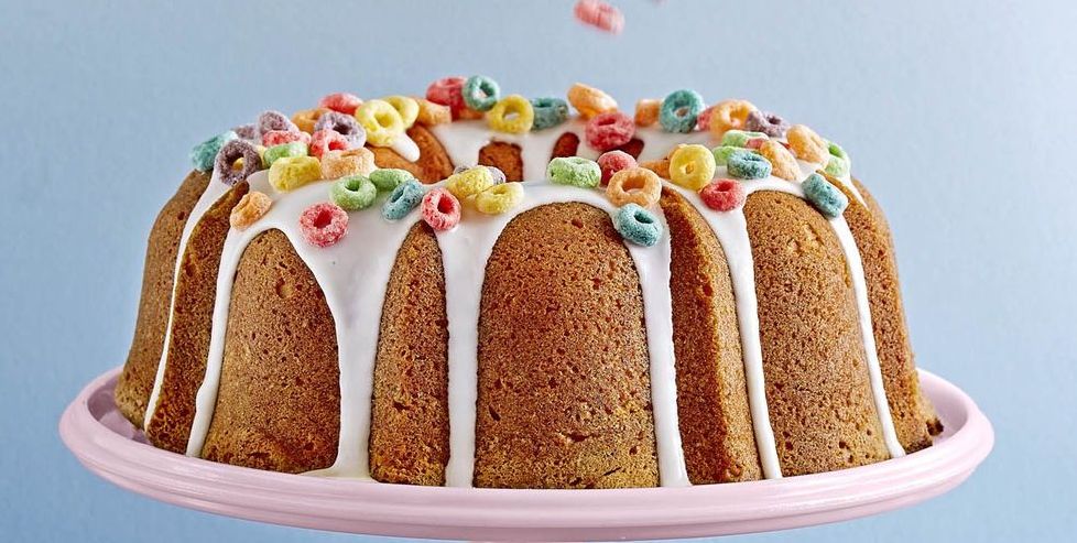 a bundt cake with a confectioners sugar glaze topped with fruit loop cereal
