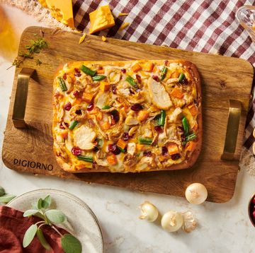 a pizza with cheese and vegetables on a cutting board