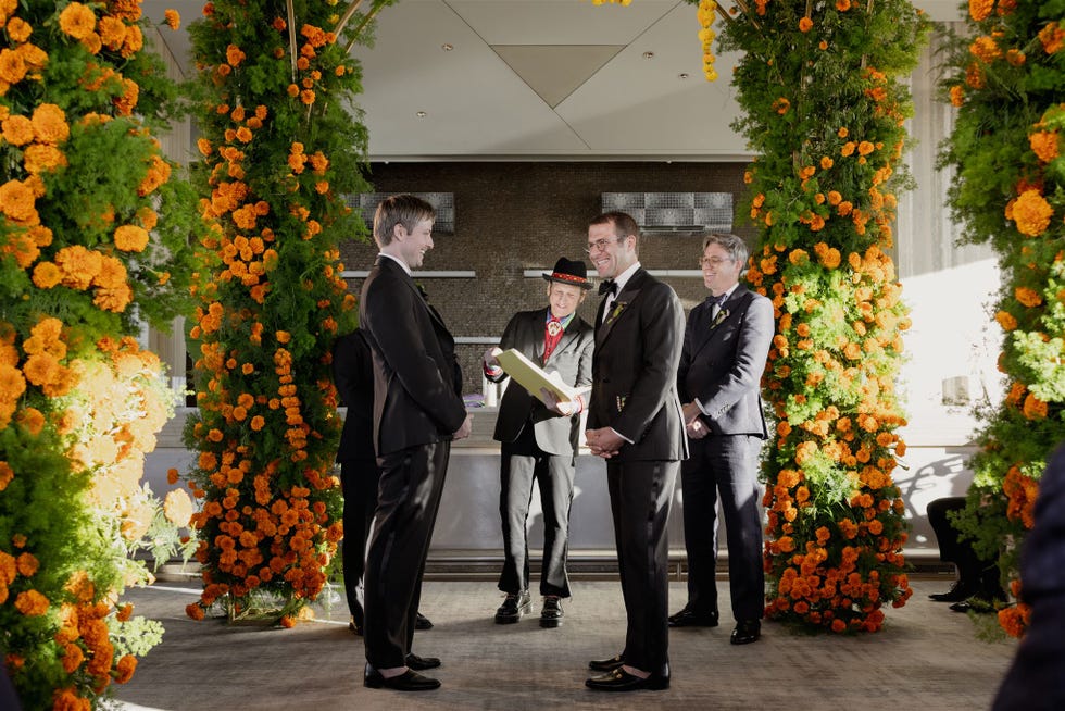 ceremonie waarbij twee personen hun geloften uitwisselen onder een bloemenboog