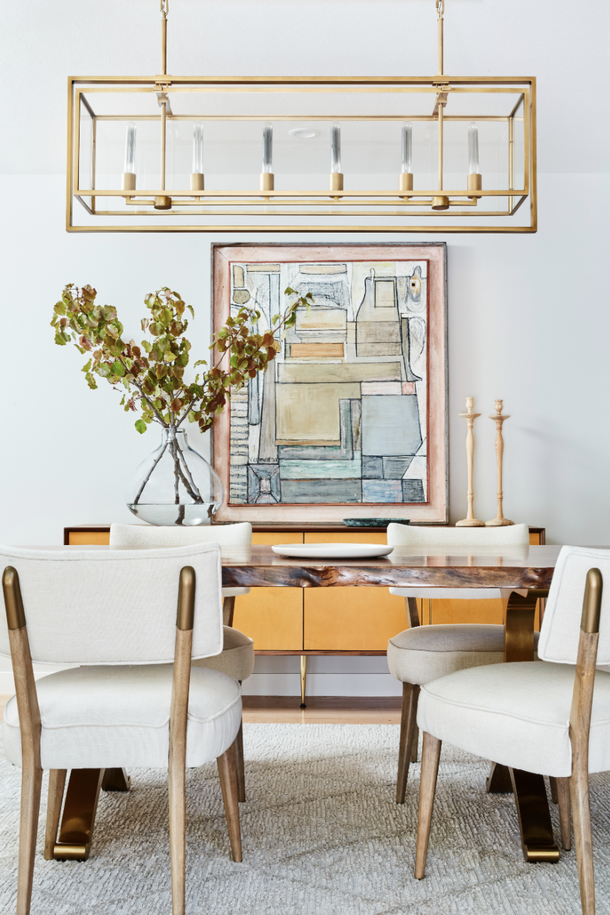 dining room details with linear gold chandelier, wood table, and yellow and brown cabinet furniture