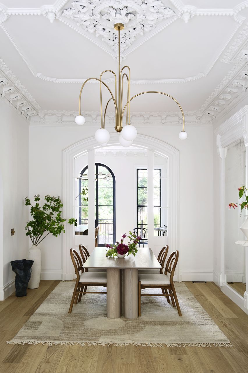 a white dining room with a chandelier over the dining table