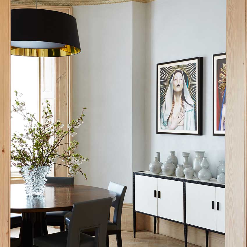 Dining room with dark wood table and chairs, white sideboard and religious artwork