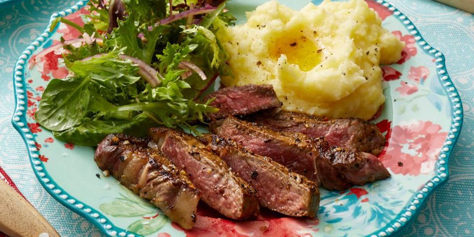 dinner ideas for two rib eye steak sliced on plate with mashed potatoes and salad