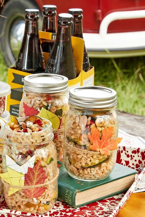 farro and acorn squash ingredients in mason jars on a red speckled tray on a table outside