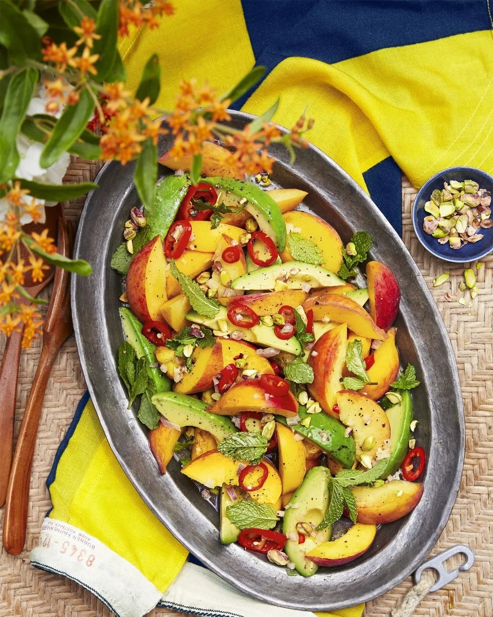 spicy peach and avocado salad on a metal serving dish on a wicker surface
