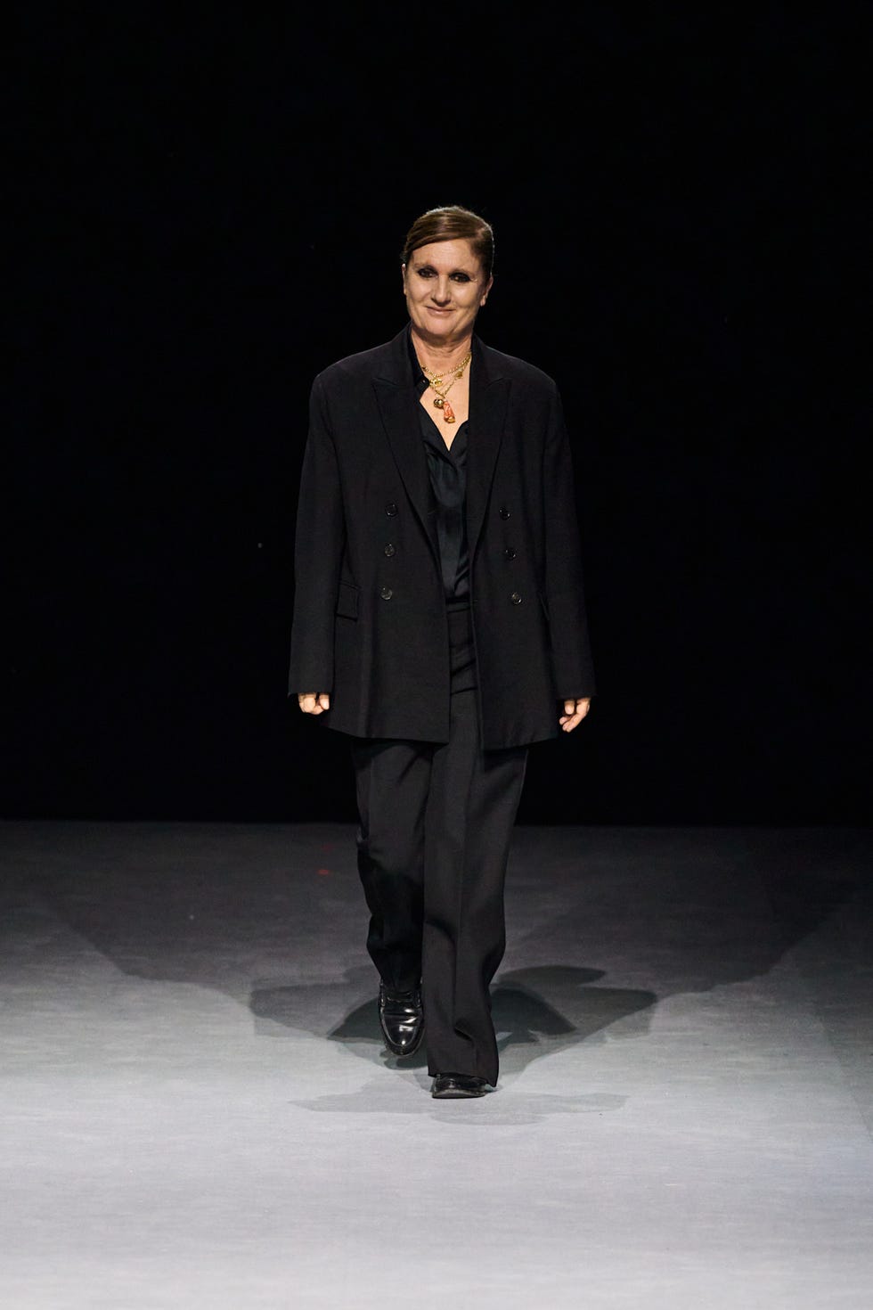 Fashion model walking on a runway in a dark outfit