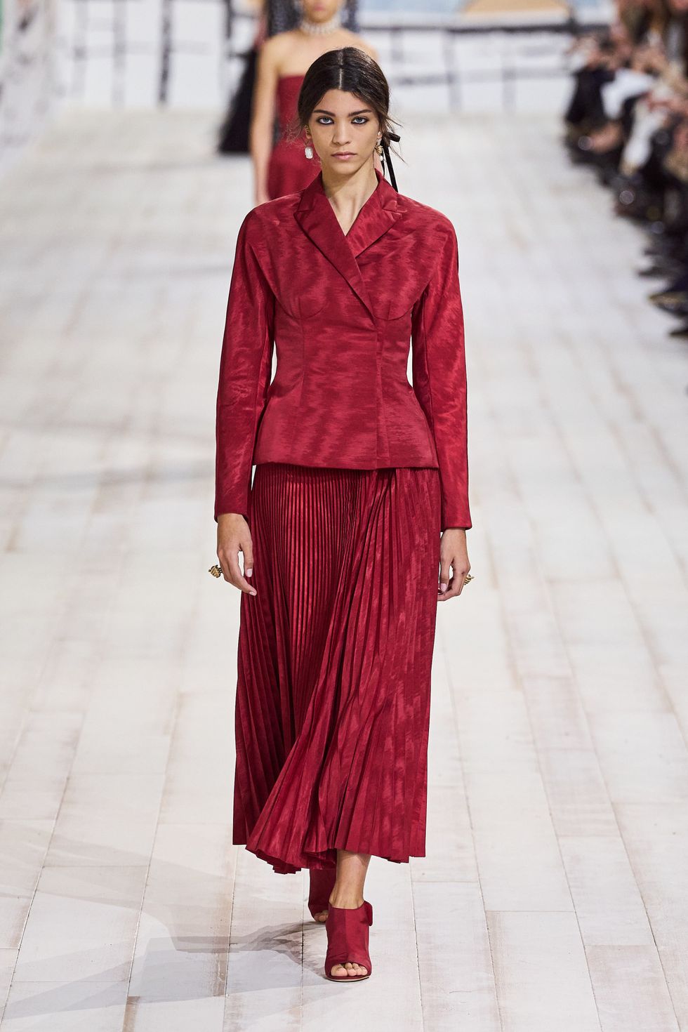 a model walks the runway in a red moire suit