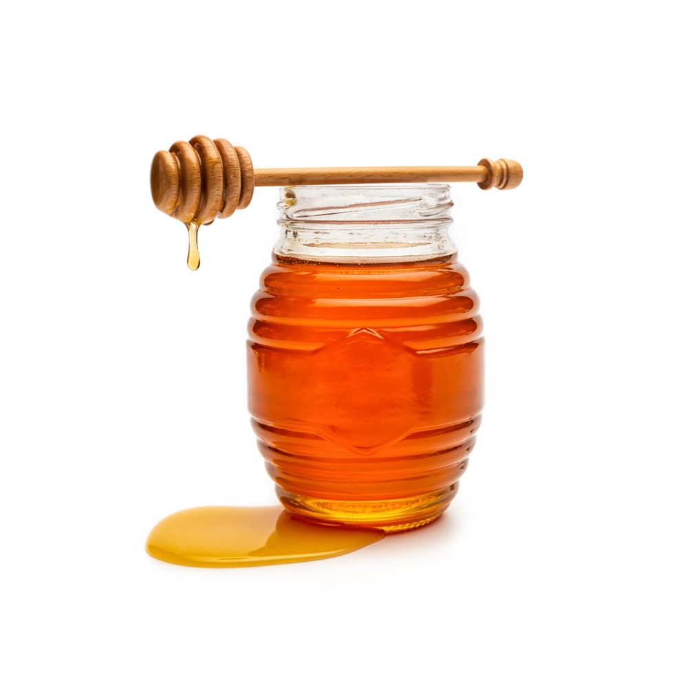 dipper over honey bottle against white background