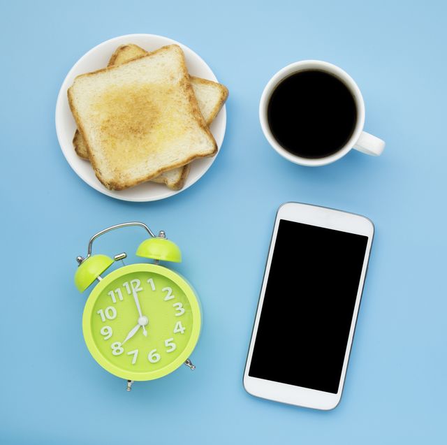 Directly Above Mobile Phone By Alarm Clock And Breakfast Over Blue Background