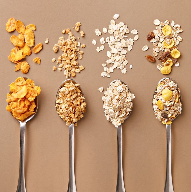directly above shot of breakfast cereals on spoons over brown background