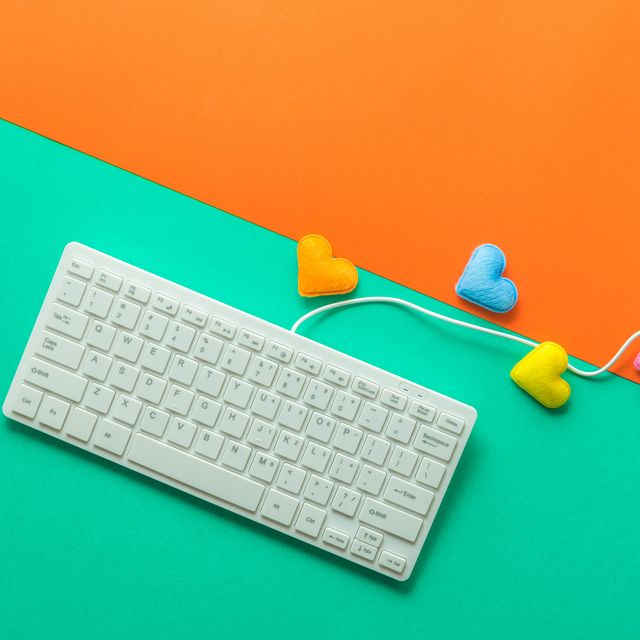 directly above shot of computer keyboard with colorful heart shapes over colored background