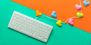 directly above shot of computer keyboard with colorful heart shapes over colored background