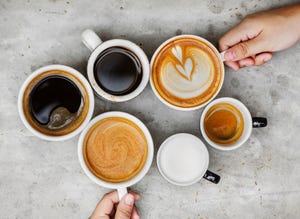 directly above shot of hands holding coffee cups on table