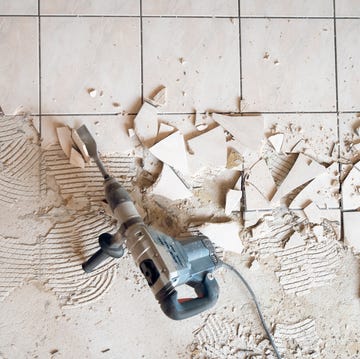 Directly Above Shot Of Jackhammer Over Broken Tile directly above shot of jackhammer over broken tile