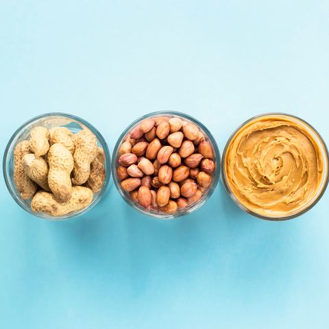 glass jars of peanuts and peanut butter on a blue background