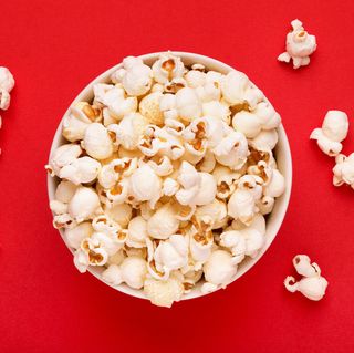 Directly Above Shot Of Popcorns In Bowl Against Red Background