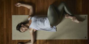 directly above shot of relaxed young woman doing yoga on exercise mat in studio