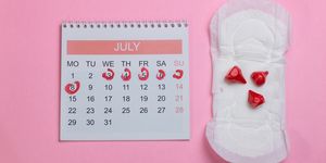 directly above shot of sanitary pad by calendar over pink background