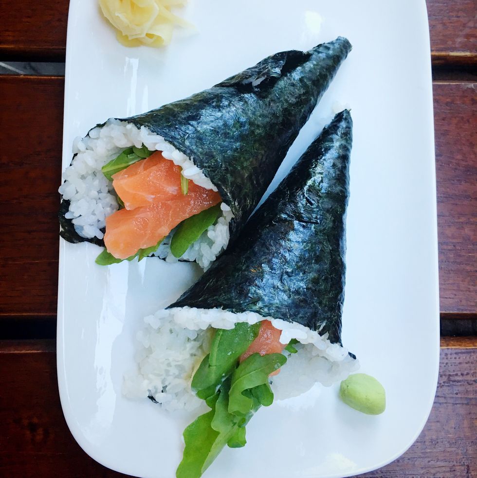 directly above shot of sushi hand rolls in plate on wooden table