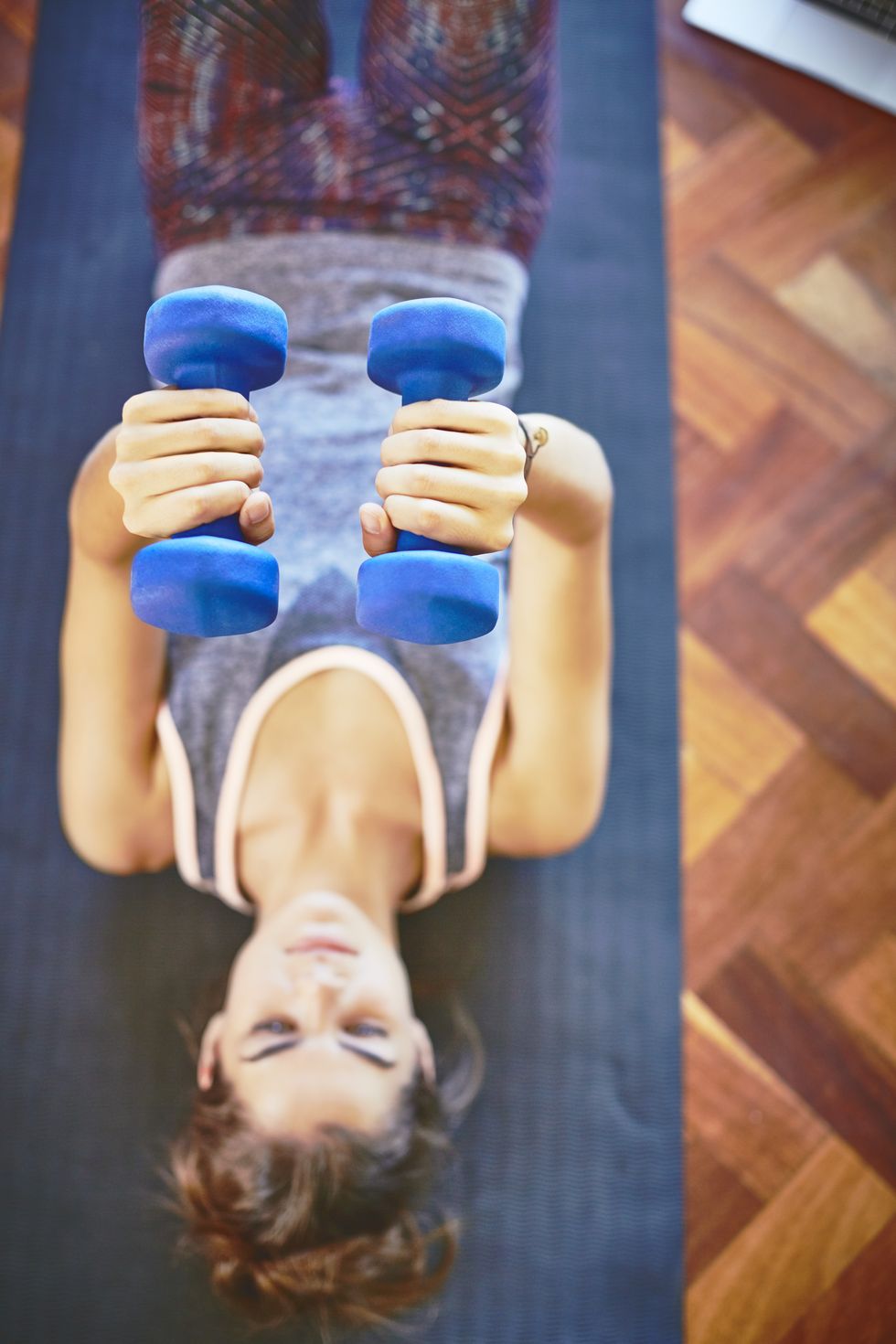 directly above shot of woman lifting dumbbells on floor