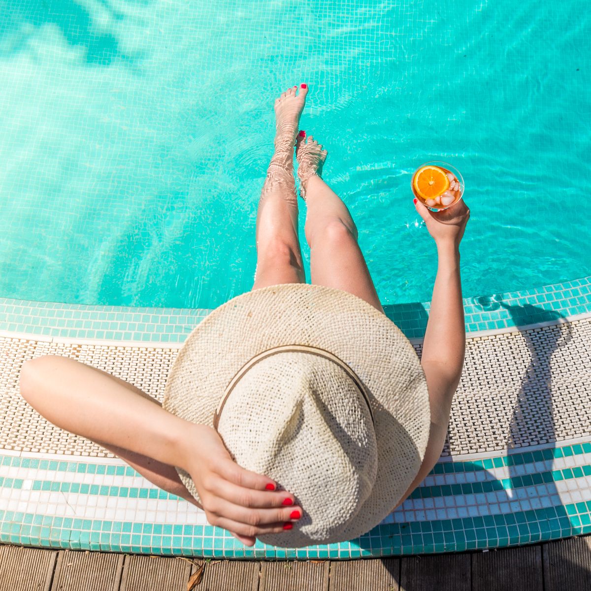 directly above shot of woman with drink sitting at poolside