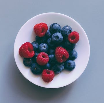 Directly above view of fresh berry fruits in bowl on gray background