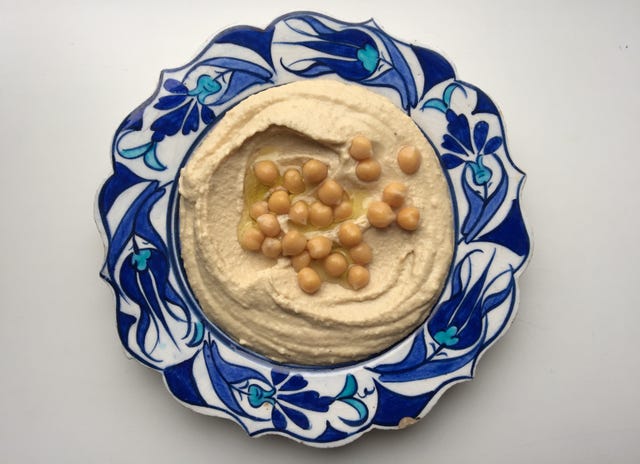 directly above view of fresh hummus with chick peas served in plate on white background