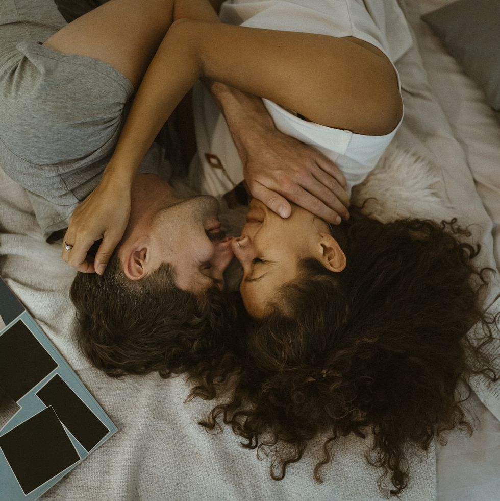 directly above view of romantic couple rubbing noses while lying on bed at home