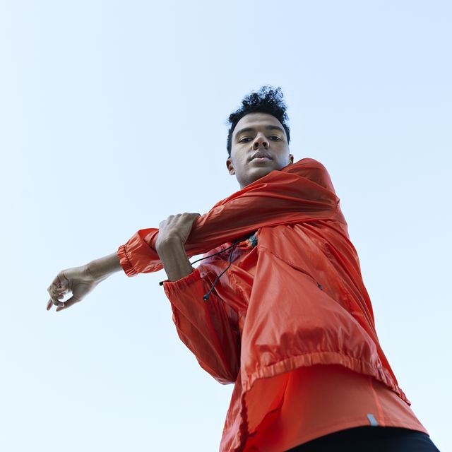 directly below portrait of athlete stretching arm against clear sky