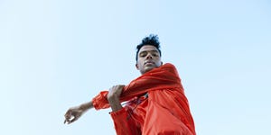 directly below portrait of athlete stretching arm against clear sky